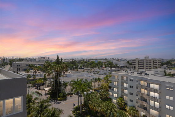 Elevated view of multiple multi-story buildings in a city landscape with a colorful sunset sky.
