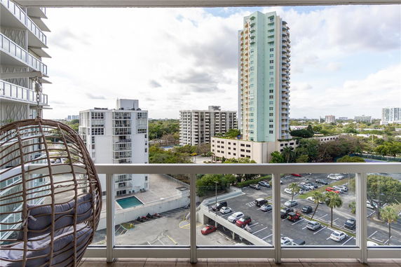 View from a balcony showing multiple high-rise buildings and a parking area.