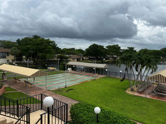 Outdoor view featuring recreational area with lush greenery and adjacent water body.