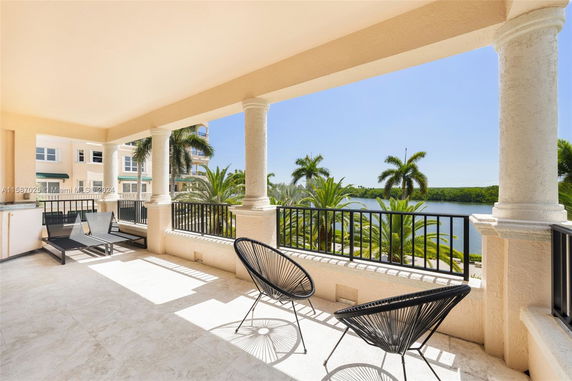 Panoramic view from a terrace overlooking palm trees and a body of water.