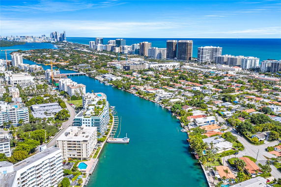Wide angle aerial view of coastal city with high-rise buildings along a waterway.