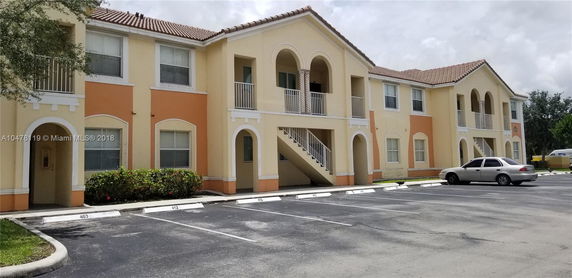 Front view of a two-story apartment building with arched balconies and a staircase.
