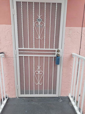 Front view of a house with a white security door and pink walls.