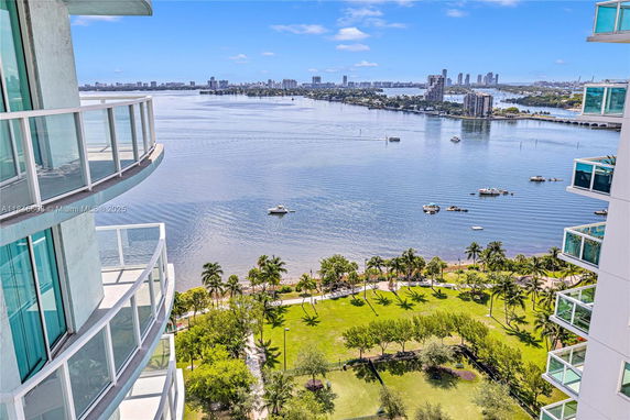 Panoramic view from a high-rise building overlooking a waterfront with boats and cityscape.