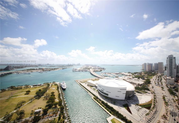 Panoramic view of a cityscape with waterway, buildings, and docked yacht.