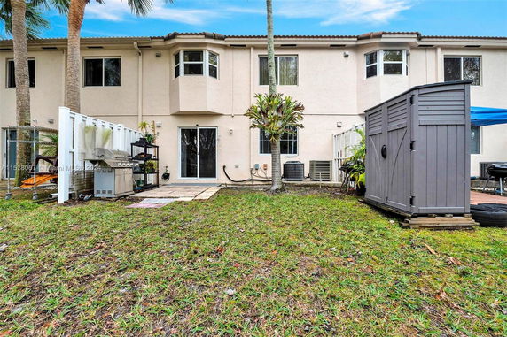 Rear view of a two-story house with sliding glass doors and small windows.