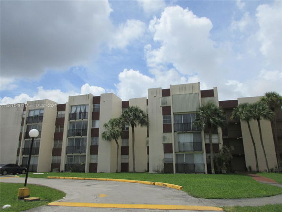 Front view of a multi-story building with glass windows and palm trees.