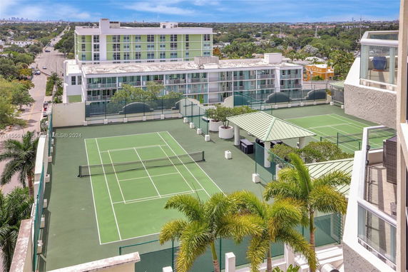 View of rooftop tennis courts with surrounding buildings and a distant city skyline.