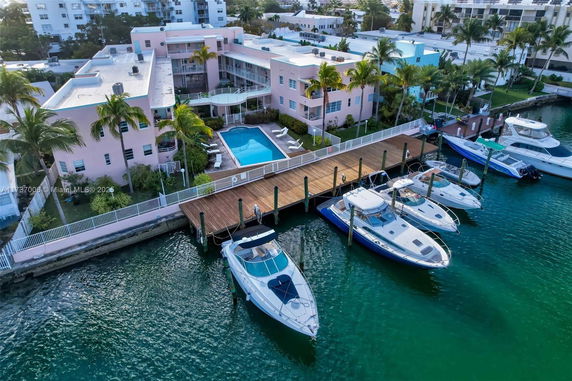 Aerial view of a waterfront building with a swimming pool and docked boats.