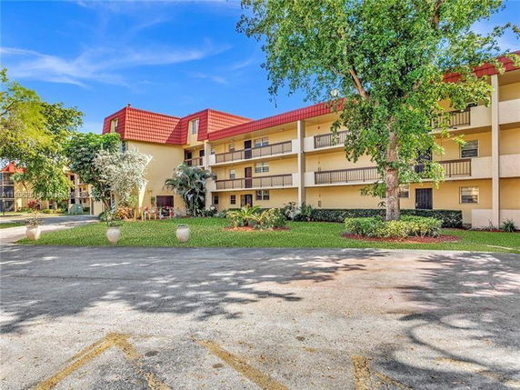 Front view of a multi-story residential building with balconies and a red roof.