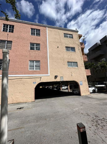 Front view of a multi-story building with parking area beneath.