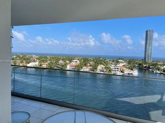 Panoramic view from a building balcony overlooking water and distant buildings.