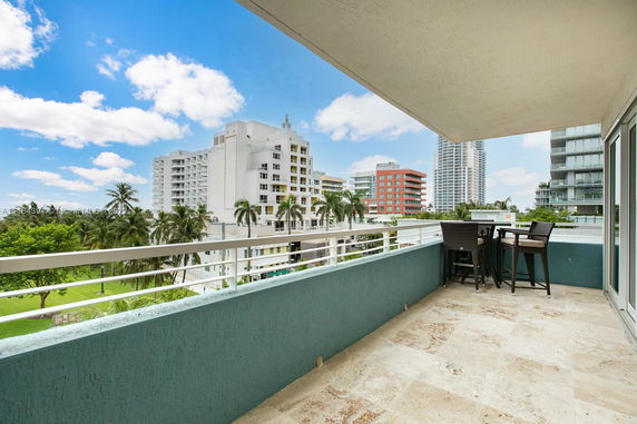 Balcony view overlooking surrounding buildings and palm trees.