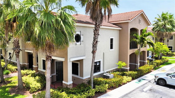 Front view of a multi-story building with a tiled roof and surrounding palm trees.