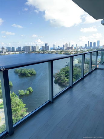 Panoramic view from a building balcony overlooking a body of water and cityscape.