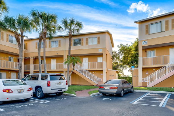 Front view of a multi-story apartment building with a staircase and parking area.