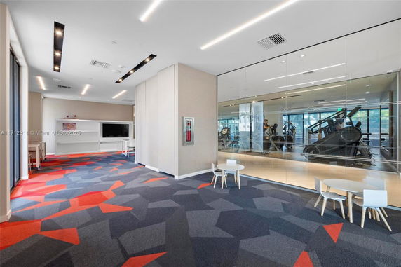 Interior view of a modern club house with gym facilities and colorful carpet.
