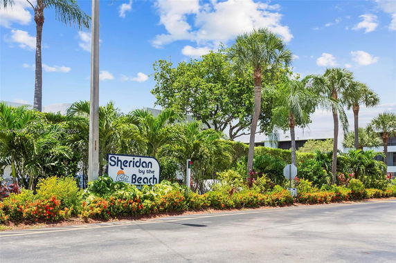 View of surrounding area with sign 'Sheridan by the Beach' in a tropical landscape.