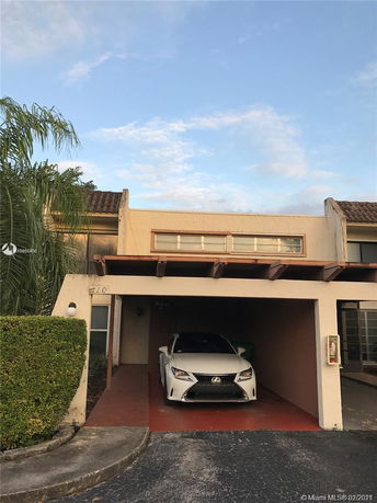 Front view of a house with a covered parking area and a car parked underneath.