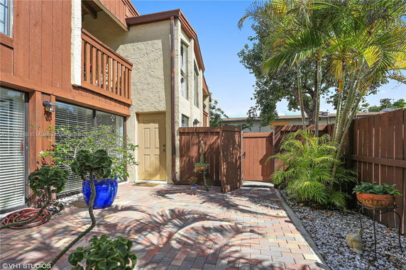 Front view of a two-story house with a wooden balcony and fenced yard.