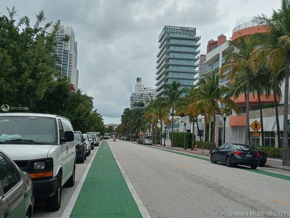 Street view with high-rise buildings and palm trees on both sides.