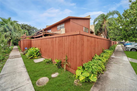 Side view of a residential building with wooden fencing and a pathway.