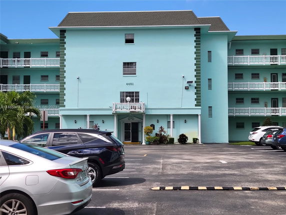 Front view of a multi-story residential building with a parking area.