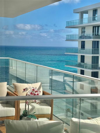 Balcony view of the ocean and adjacent modern building with glass railings.