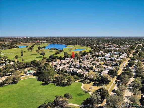 Wide-angle aerial view of a residential area with nearby green spaces and bodies of water.