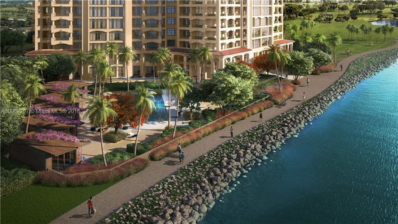View of a multi-story building near the water with landscaped gardens and pathways.