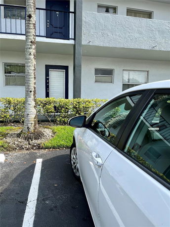 Outdoor parking space with a white car parked near a building.