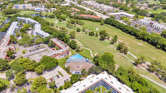 Aerial view showing multiple buildings and a large expanse of green fields and trees.