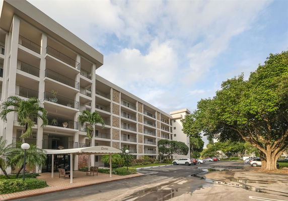 Front view of a multi-story residential building with balconies and a covered entrance.