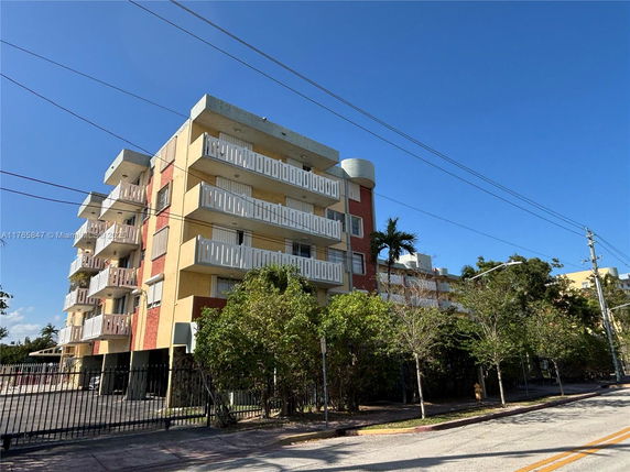 Front view of a multi-story residential building with balconies and gated entrance.