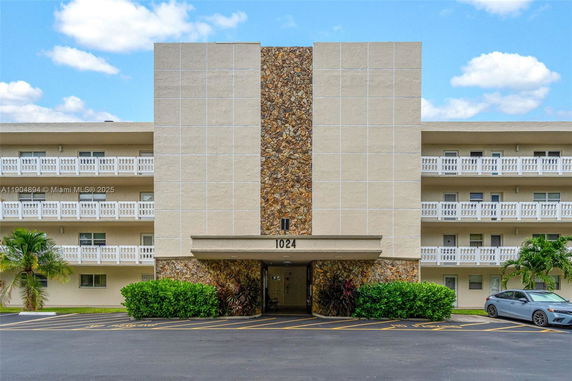 Front view of a multi-story building with a stone facade and balcony railings.
