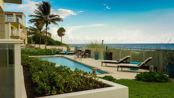 Outdoor swimming pool area with lounge chairs and ocean view.