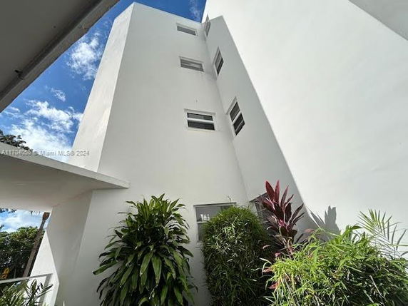 View of a white multi-story building exterior with several plants in the foreground.