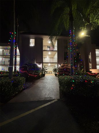 Front view of a multi-story building with balconies, decorated with colorful lights at night.