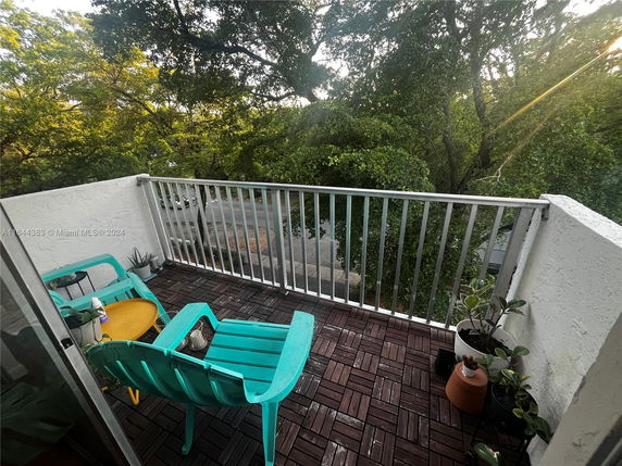 Balcony view with green trees surrounding the area.