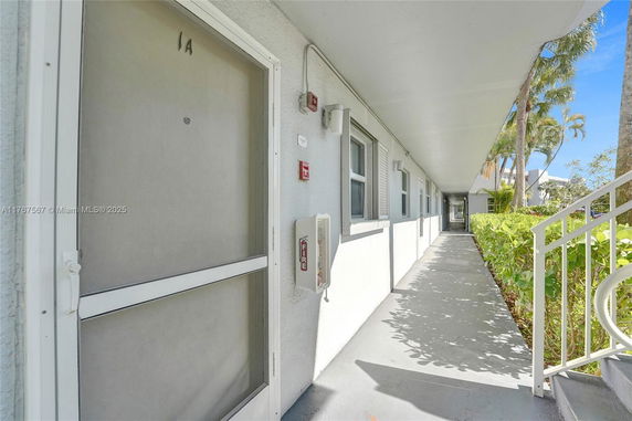 Exterior corridor of a building with multiple doors and windows.