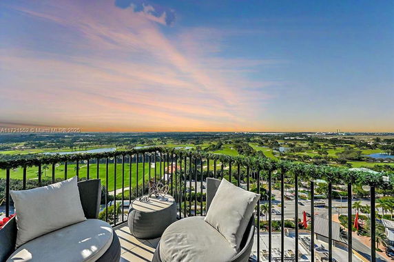 Panoramic view of landscape seen from a balcony with railings and outdoor seating.