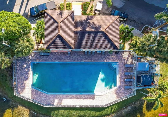 Aerial view of a swimming pool adjacent to a building with a tiled roof.