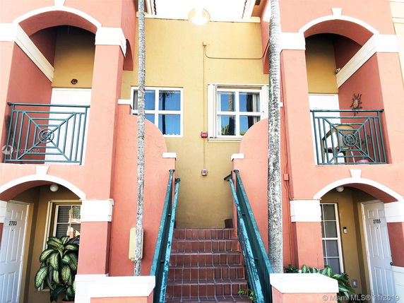 Front view of a multi-story building with dual staircases and decorative balconies.