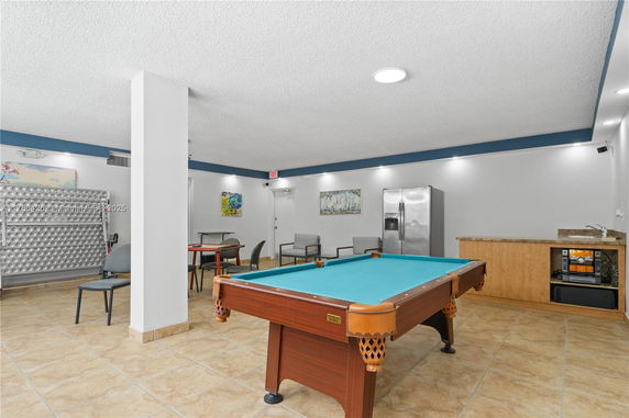 Recreational room with a pool table, chairs, tables, a refrigerator, and a sink.