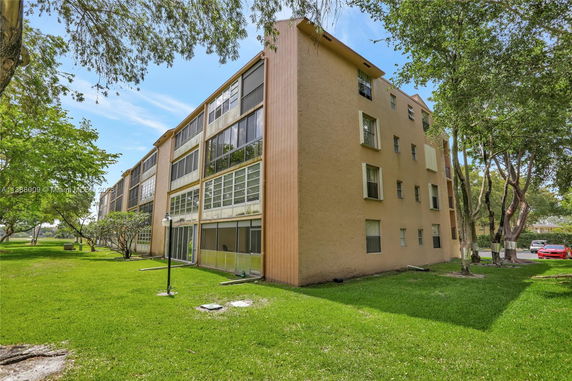 Front view of a multi-story residential building with large glass windows.