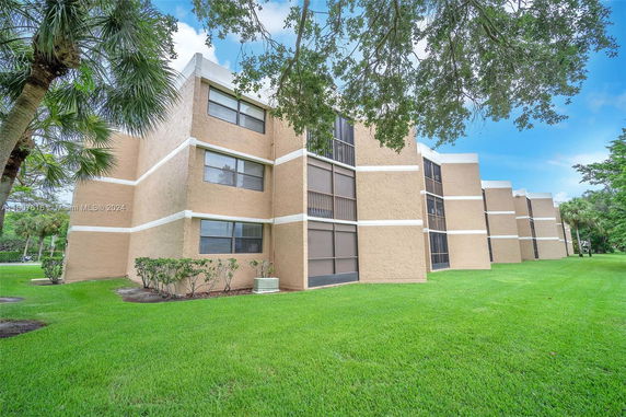 Side view of a multi-story building with beige exterior and screened windows.