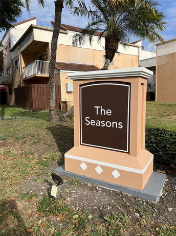 Front view of a two-story building with balconies and a large sign reading 'The Seasons' in the foreground.