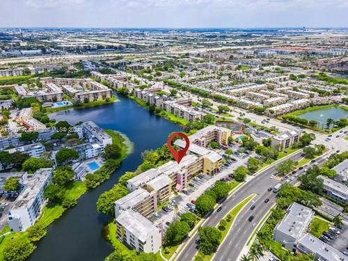Aerial view of a residential area with multiple apartment buildings near a body of water, surrounded by roads and greenery.