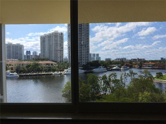 View of surrounding areas with tall buildings and waterway, seen from a window.