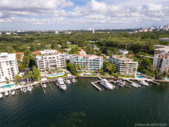 Aerial view of waterfront apartment buildings with private docks and boats.